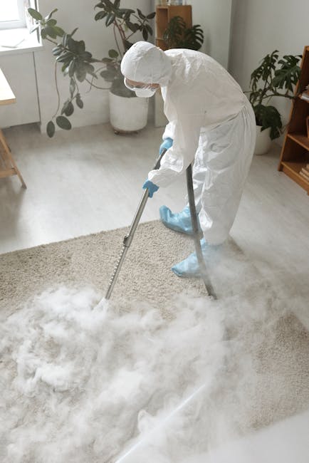 A person is kneeling on a patterned carpeted floor, using a yellow and black vacuum cleaner to perform surface cleaning and deep cleaning of a residential carpet. The vacuum cleaner's open dust compar
